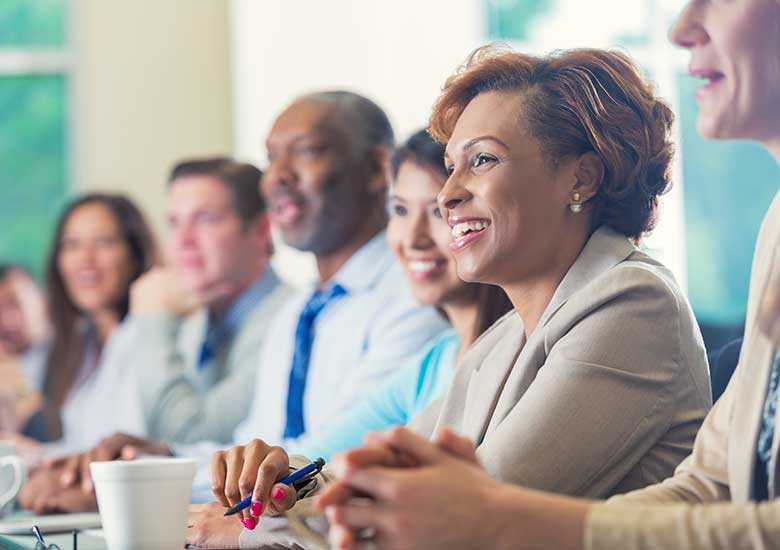 A group of people sitting a conference table and smiling